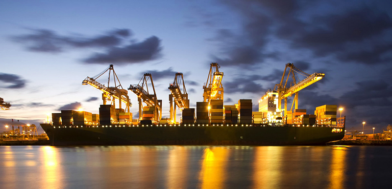 Shipping containers being loaded at night at port - Freight Forwarder